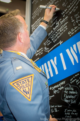 Lt. Craig Costello from New Jersey State Police signs Vigilant's Why I Wear the Badge wall at IACP 2016.