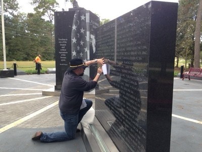 A warrior uses a pencil and paper to create a keepsake at the Fallen Warriors Memorial in Houston.