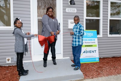 New homeowner Christina Thomas cuts the ribbon in front of her new home, built by global automotive seating supplier Adient through Habitat for Humanity of Huron Valley. Excited to help are her children, Chanel, 7 and Cam'ron, 10.